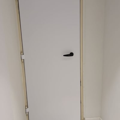 דלת לבנה עם ידית שחורה במסגרת קיר