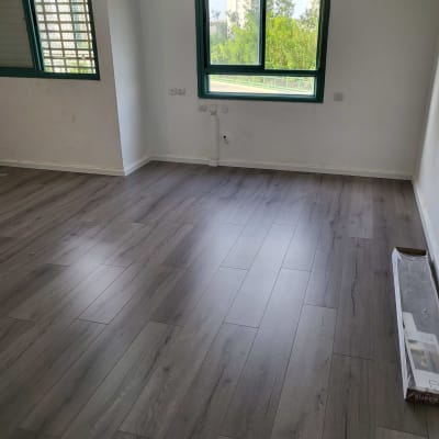רצפת פרקט עץ כהה בחדר ריק עם חלונות