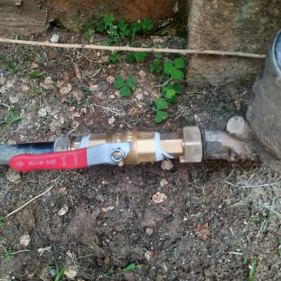 ברז מים עם ידית אדומה מחובר לצינור מתכת