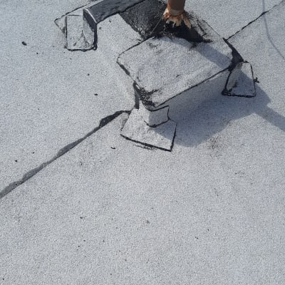 איטום גג עם זפת סביב צינור מתכת.