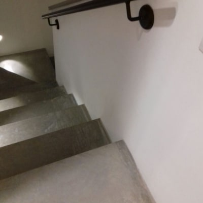 מעקה מתכת שחור על קיר מדרגות לבן