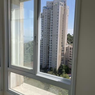 חלון אלומיניום עם מסגרת לבנה ונוף עירוני