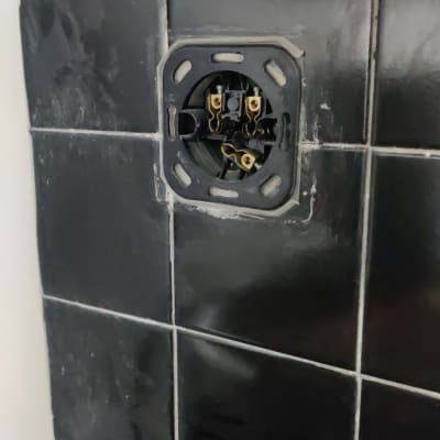 שקע חשמלי פתוח בקיר אריחים שחורים