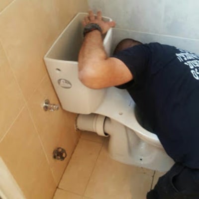 אדם מתקן אסלה בחדר אמבטיה