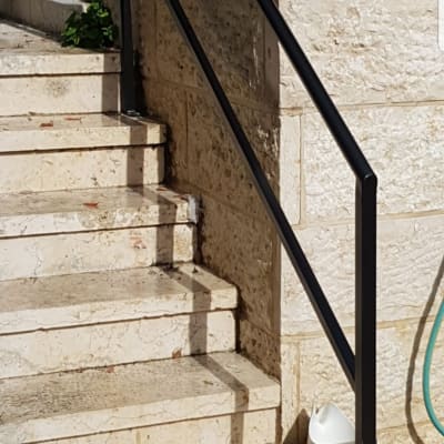 מעקה מתכת שחור על מדרגות אבן חיצוניות