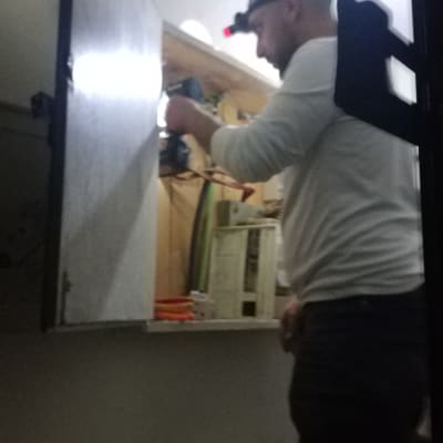 חשמלאי עובד עם פנס ראש וארון חשמל פתוח