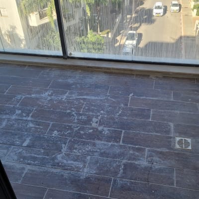 מרפסת עם רצפה מלוכלכת וזכוכית עם סימני מים