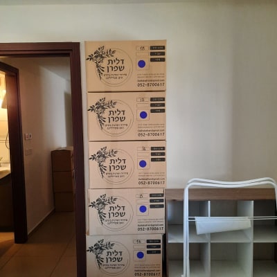 שישה ארגזי קרטון מסודרים ליד מדף לבן