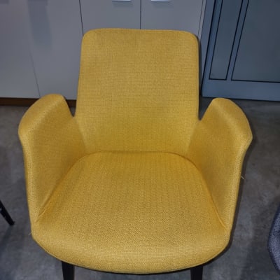 כיסא בד צהוב עם רגליים שחורות על רצפה אפורה