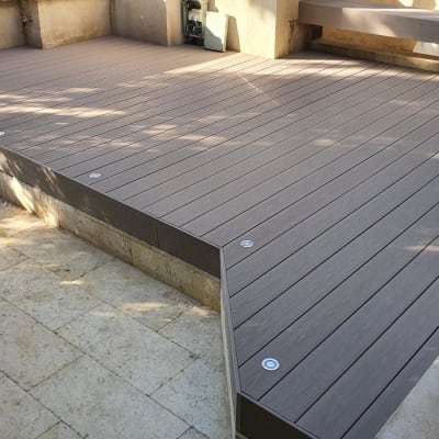 דק עץ חום עם ברגים על רצפת אבן