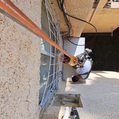 אדם מבצע איטום חיצוני על קיר בניין