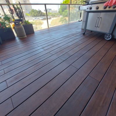 רצפת עץ במרפסת עם גריל גז וצמחים