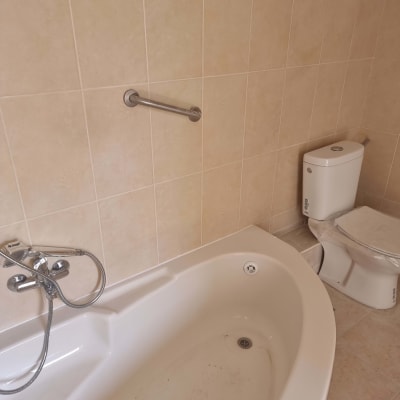 אמבטיה עם ברז ומקלחת, שירותים וקיר אריחים