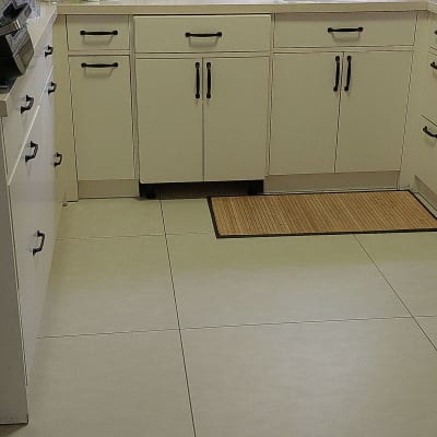 מטבח עם ארונות לבנים, כיור וברז, מוצרי ניקוי על השיש