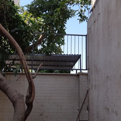 מעקה מתכת על קיר חיצוני עם עץ ברקע