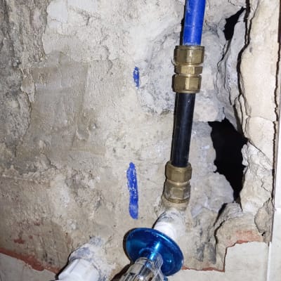 צינור כחול ושחור עם מחברים בקיר חשוף