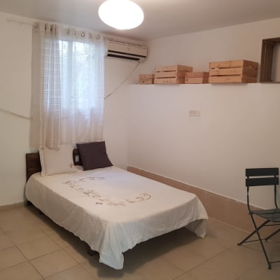 מיטה עם מצעים לבנים וכריות, קופסאות עץ על מדף