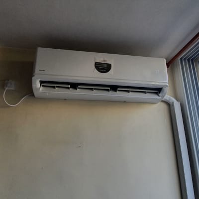 מזגן מותקן על קיר ליד חלון פתוח