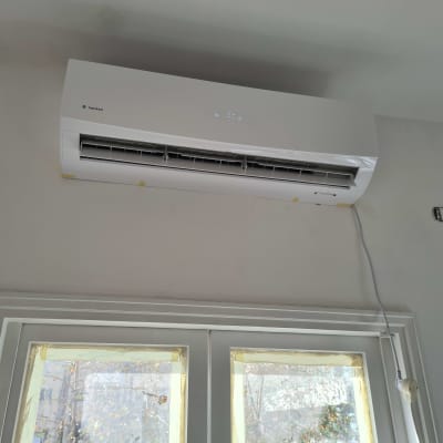 מזגן מותקן על קיר מעל חלון עם כבל חשמל