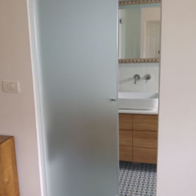 חדר אמבטיה עם דלת זכוכית חלבית פתוחה