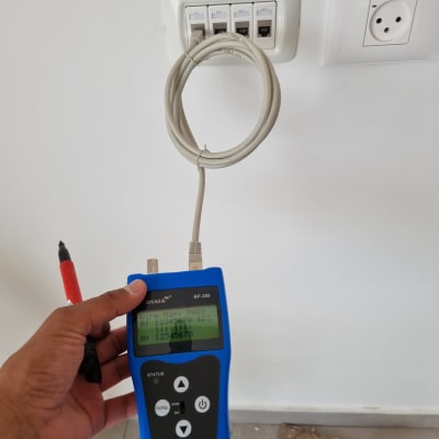 טכנאי רשת בודק כבל עם מכשיר בדיקה כחול