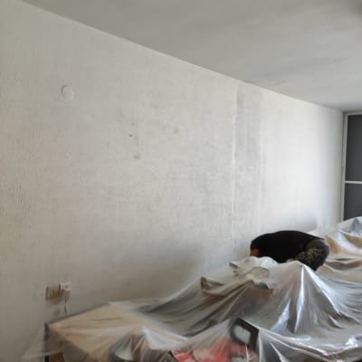 קיר צבוע בלבן עם רהיטים מכוסים בניילון