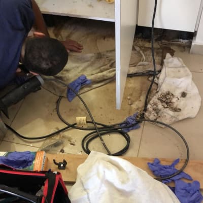 אדם עובד מתחת לכיור עם כלים וצינורות