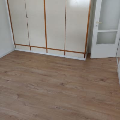 רצפת עץ חדשה בחדר עם ארון ודלת לבנה