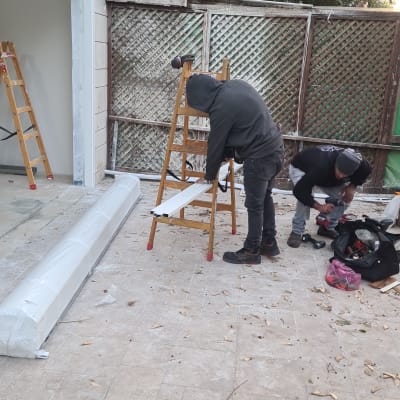 שני אנשים עובדים עם פרופילי אלומיניום על סולם