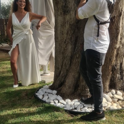 צלם מצלם אישה בשמלה לבנה ליד עץ