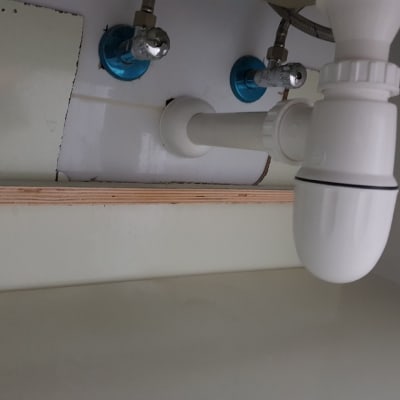 צנרת פלסטיק מתחת לכיור עם ברזים כחולים