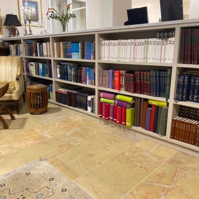 ספרים על מדפים בחדר עם כורסה ושולחן קטן