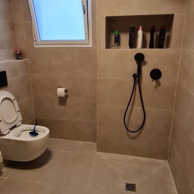 חדר אמבטיה עם מקלחון, שירותים, אריחים חדשים ומקלחת יד.