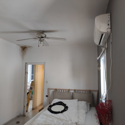 סולם צהוב ליד קיר עם כתם רטיבות