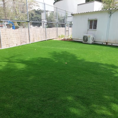 דשא סינתטי ירוק בחצר מגודרת
