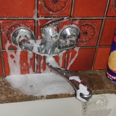 ברז מטבח עם סבון ומים זורמים בכיור