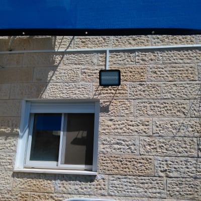 תאורת חוץ מותקנת על קיר אבן עם כבלים חשמליים