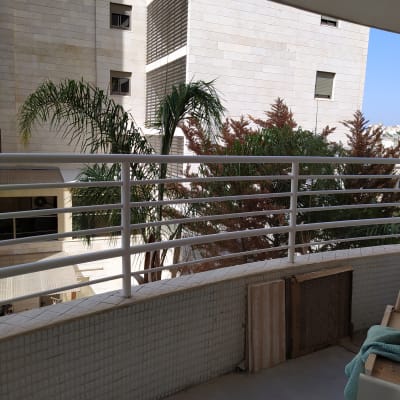 מעקה מתכת לבן עם מסגרות עץ מונחות בצד