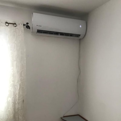 מזגן מותקן על קיר לבן עם כבל חשמל