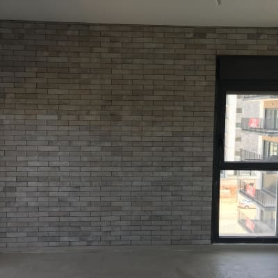 קיר לבנים אפור וחלון גדול בחדר ריק