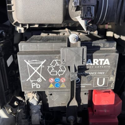 מצבר רכב עם סמלים ואזהרות על גבי המכסה