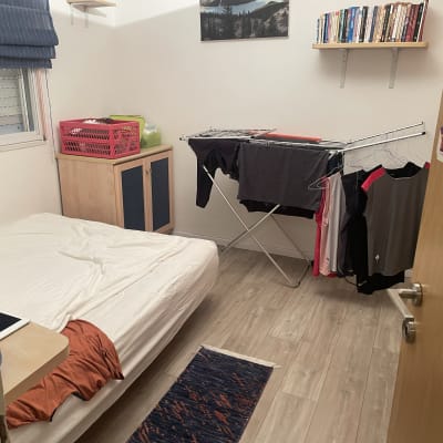 חדר עם רצפת פרקט, מיטה ומתקן ייבוש בגדים