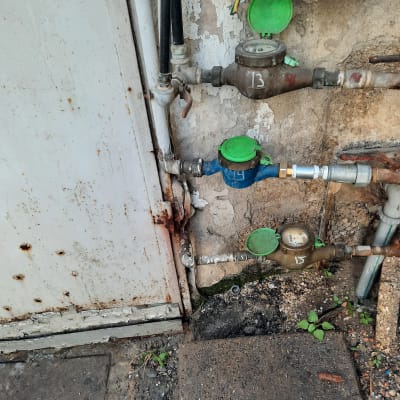 מד מים עם מכסים ירוקים על קיר חיצוני