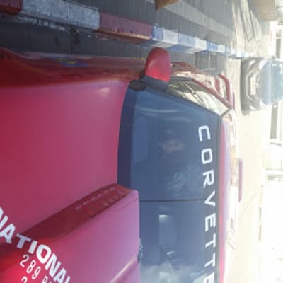 מכונית קורבט אדומה עם מדבקות על השמשה הקדמית