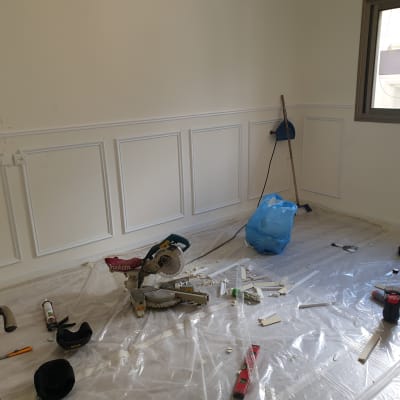 מסור חשמלי, מקדחה, כלי עבודה וחומרים על רצפה מכוסה בניילון