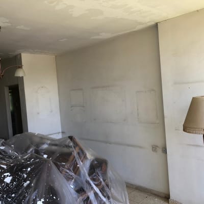 קיר עם סימני תיקון צבע, רהיטים מכוסים בניילון