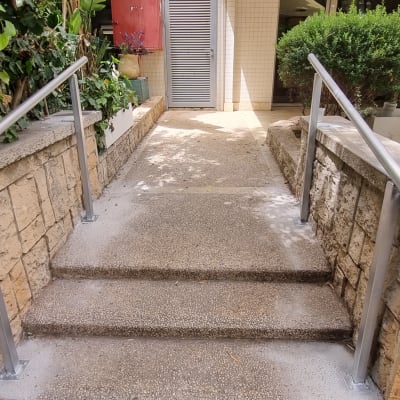 מעקה מתכת לאורך מדרגות אבן בכניסה לבניין