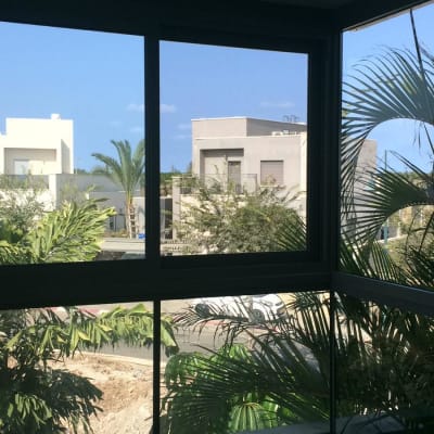 חלון אלומיניום עם נוף חיצוני של עצים ובניינים