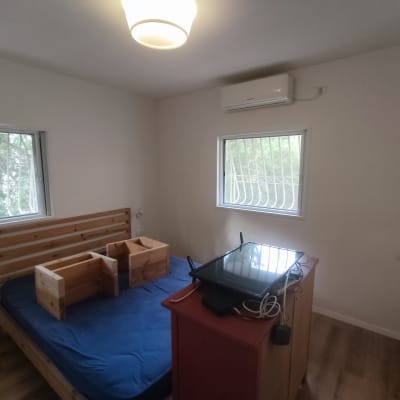 חדר עם מיטה, קופסאות עץ ומסך על שידה