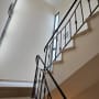 מדרגות עם מעקה מתכת וקיר צבוע בלבן